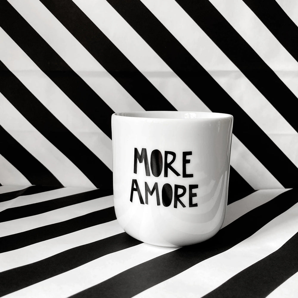 Weißer Keramikbecher ohne Henkel mit schwarzem Schriftzug ‚More Amore‘ – minimalistischer Designbecher aus Keramik.