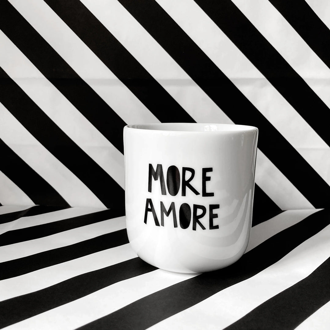 Weißer Keramikbecher ohne Henkel mit schwarzem Schriftzug ‚More Amore‘ – minimalistischer Designbecher aus Keramik.