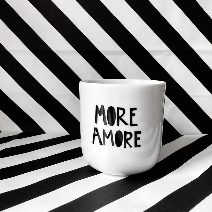 Weißer Keramikbecher ohne Henkel mit schwarzem Schriftzug ‚More Amore‘ – minimalistischer Designbecher aus Keramik.